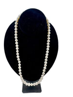 Elegant pearl necklace displayed on a black stand, highlighting timeless style and sophistication—perfect for trending fashion statements and adding a touch of class to any outfit. 