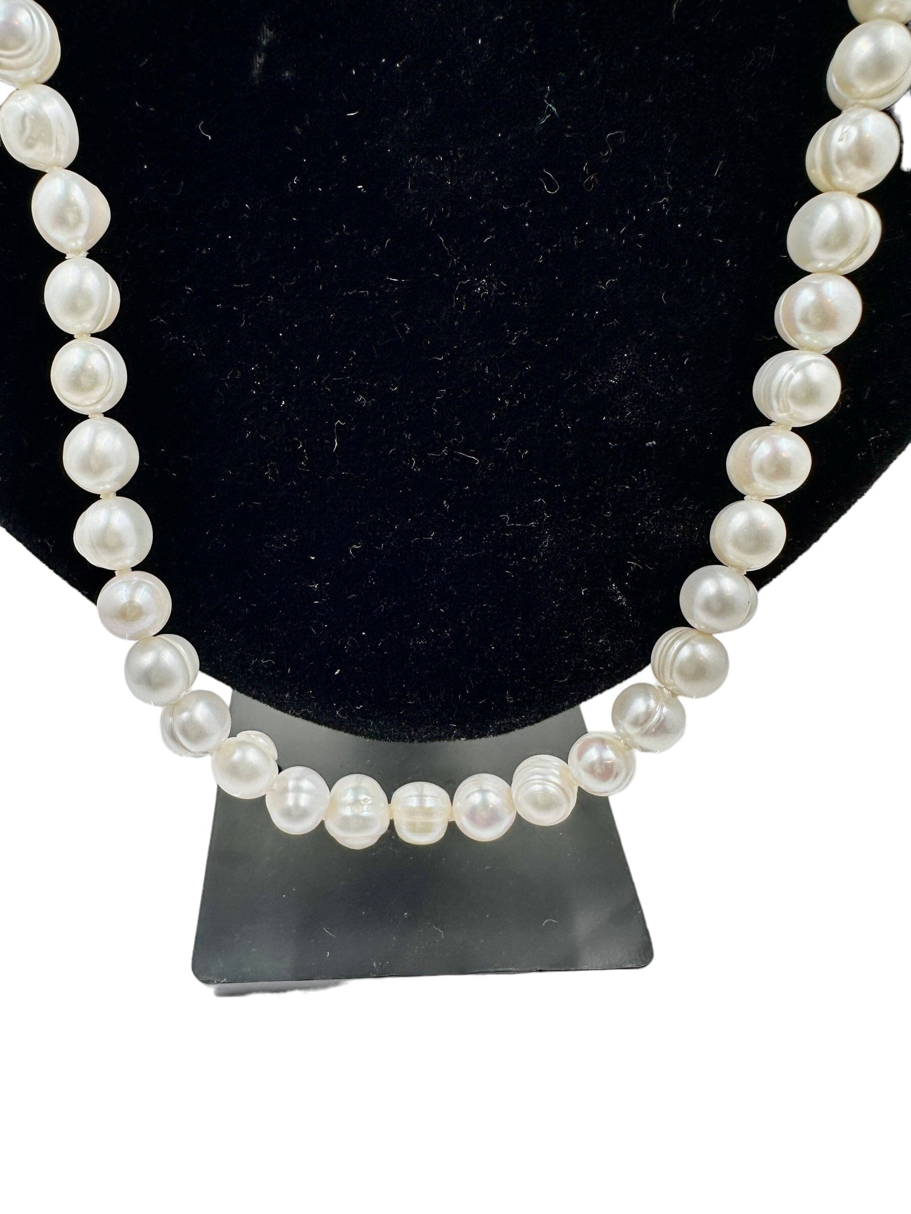 Elegant pearl necklace displayed on a black stand, showcasing lustrous pearls in a timeless design, perfect for chic and sophisticated fashion statements. 