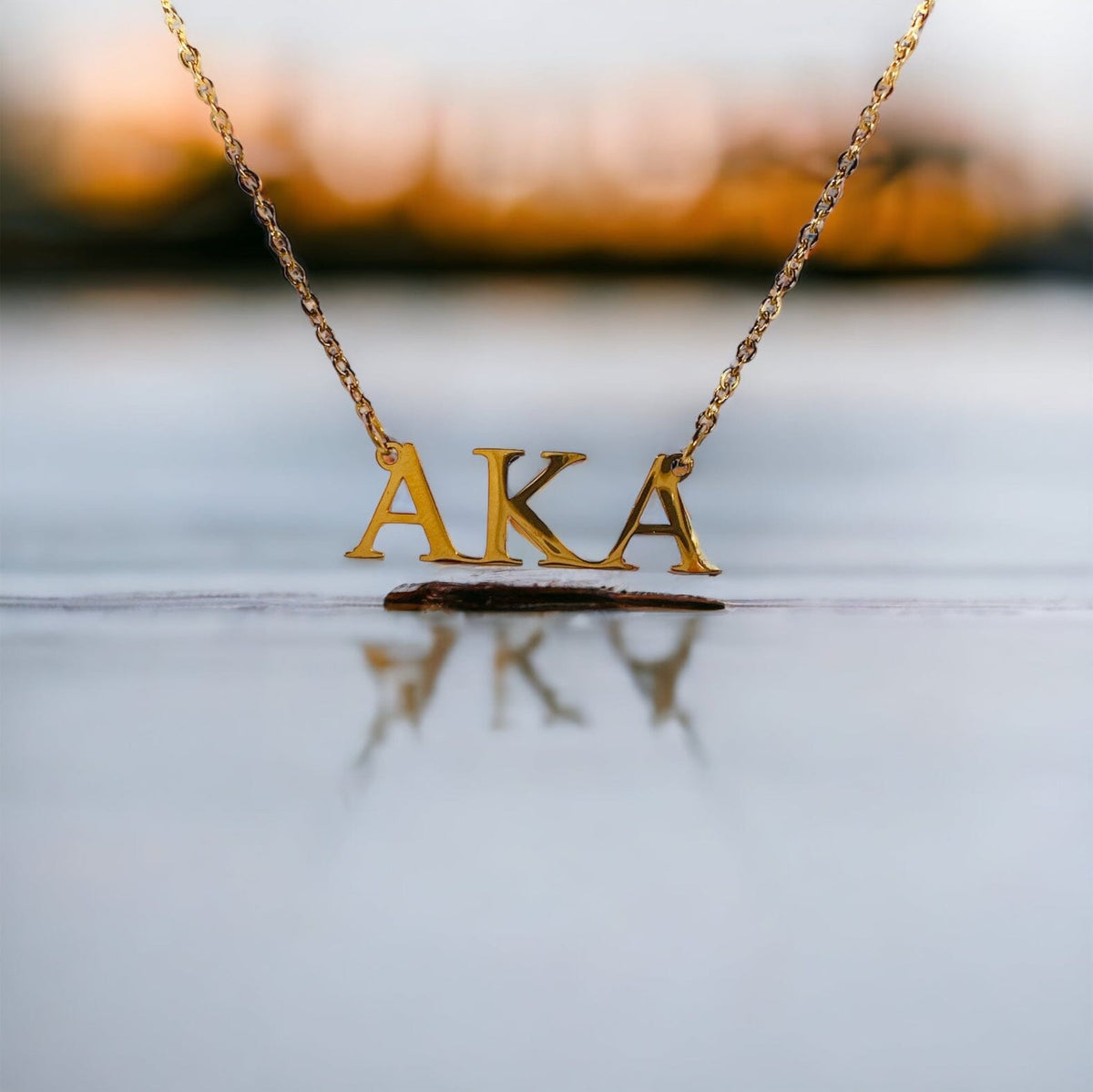 Close-up of a gold-plated stainless steel necklace with letters "AKA" suspended on a chain, perfect for showcasing Alpha Kappa Alpha pride.