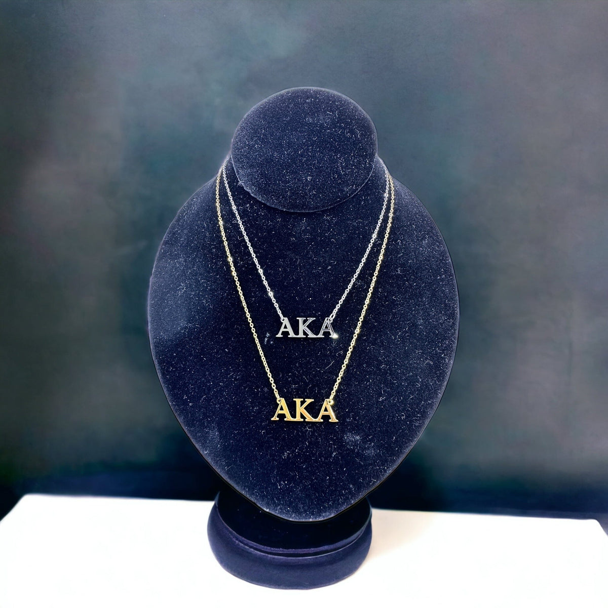 Elegant AKA Necklace with 18k gold and polished silver options, displayed on a black mannequin against a sophisticated background.