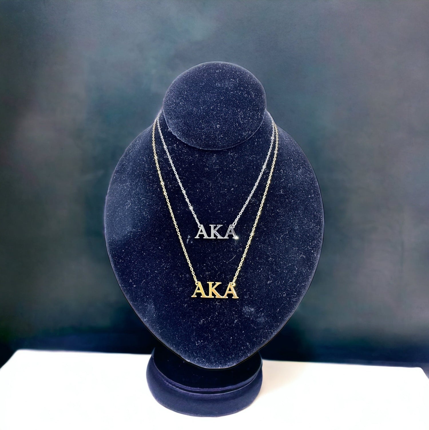 Elegant AKA Necklace with 18k gold and polished silver options, displayed on a black mannequin against a sophisticated background.