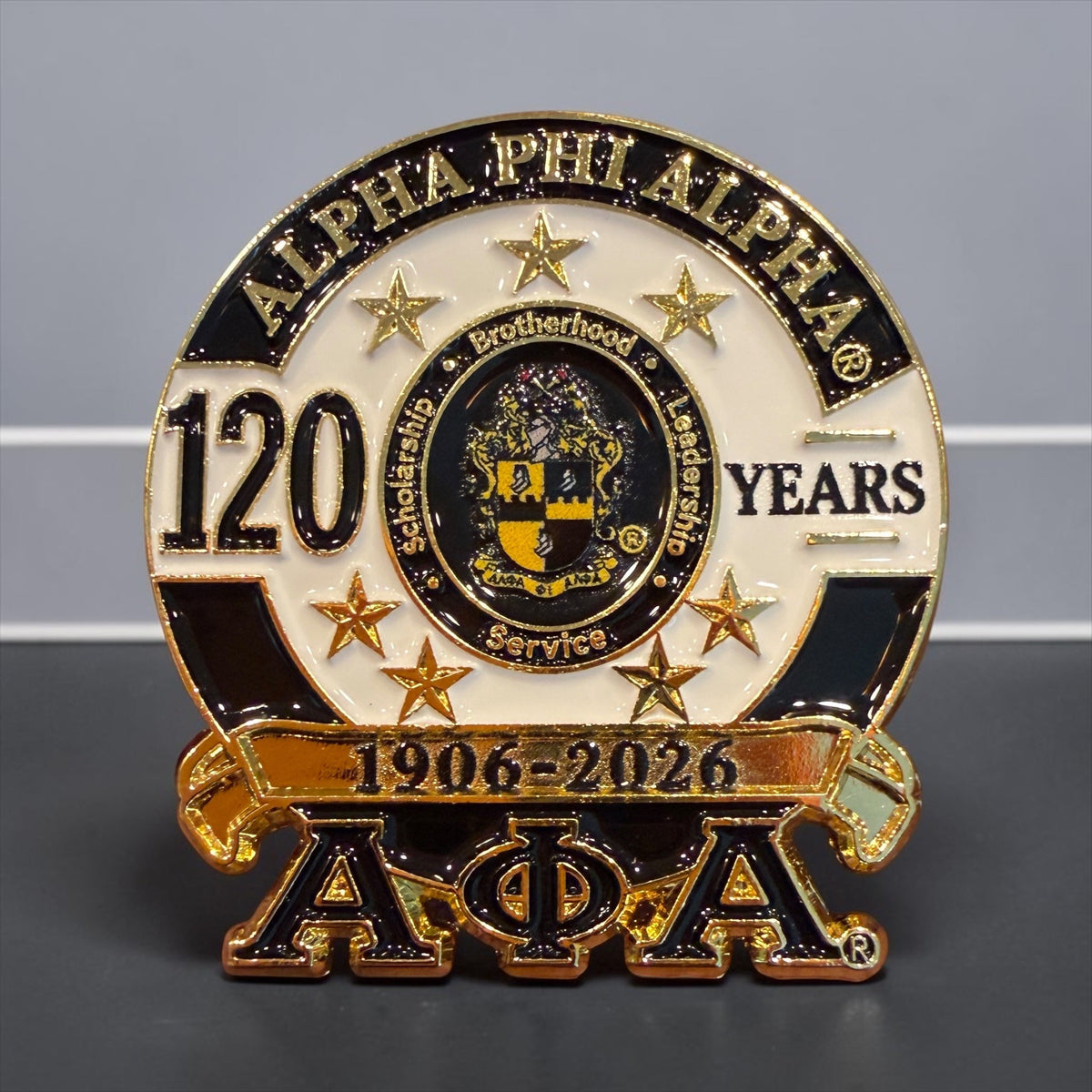Alpha Phi Alpha 120th anniversary lapel pin with fraternity crest, seven gold stars, 1906-2026 banner and Greek letters