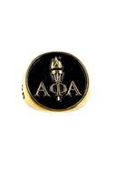 Alpha Phi Alpha Light of the World gold ring with iconic A Phi A Greek letters and torch design on a black background, crafted in brass and PVD plated in 18k gold.