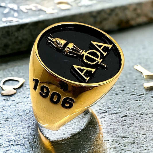 Alpha Phi Alpha Light of the World gold ring with black enamel background, featuring the fraternity's Greek letters and torch design, and engraved with "1906".