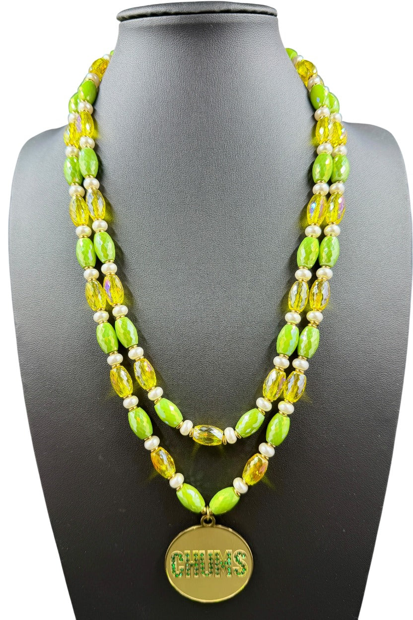 Chums double strand necklace with yellow and green stones and gold-plated CHUMS medallion on a black bust