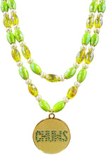 Close-up of gold-plated Chums medallion with CHUMS spelled in green CZ stones on yellow and green beaded strands