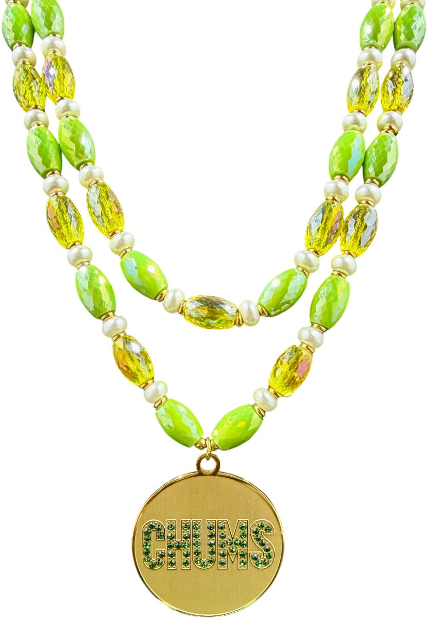Close-up of gold-plated Chums medallion with CHUMS spelled in green CZ stones on yellow and green beaded strands
