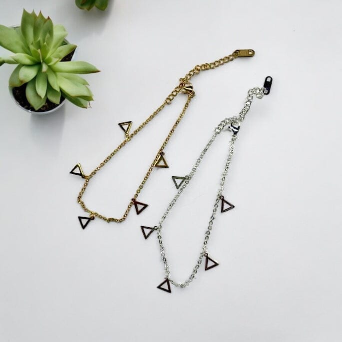 Two Delta Sigma Theta Triangle Charm Ankle Bracelets in stainless steel, gold, and silver color options, adorned with multiple triangle charms, displayed against a white background with a succulent plant for decor.