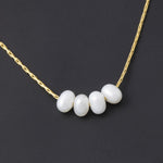 Close-up of four white glass pearls on an 18K gold plated stainless steel chain