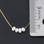 Dainty gold glass pearl necklace next to a ruler showing the pearl size