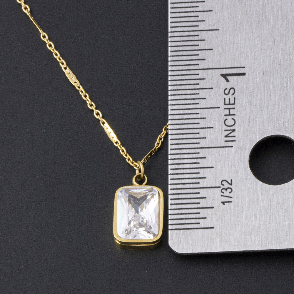 Gold rectangle CZ pendant next to a ruler showing its size