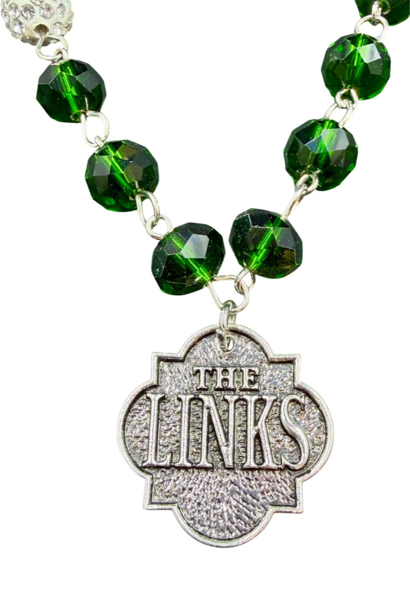 Close-up of silver THE LINKS quatrefoil charm on green crystal bead bracelet