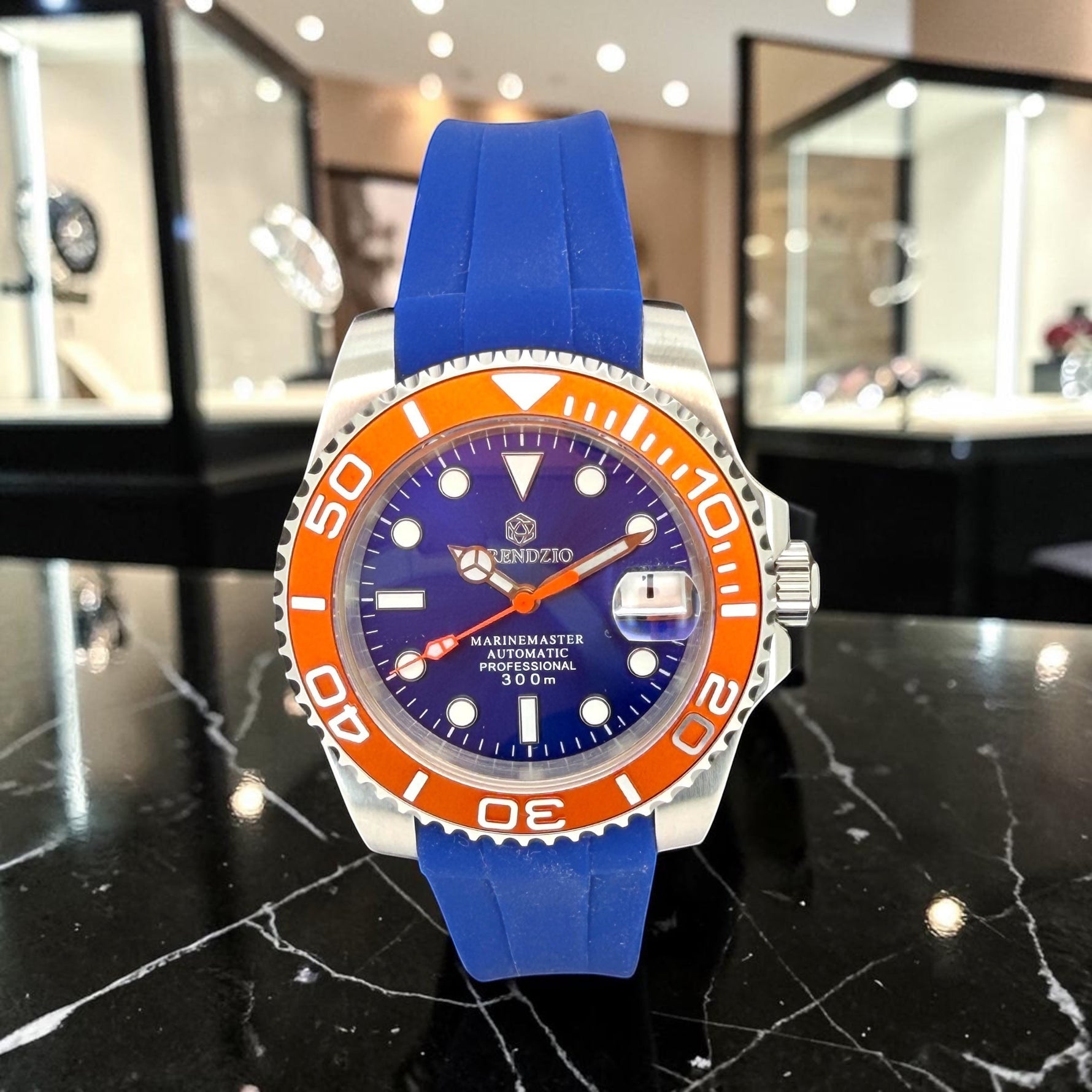 Trendzio Jewelry blue amber automatic stainless steel watch with orange bezel and blue rubber strap.