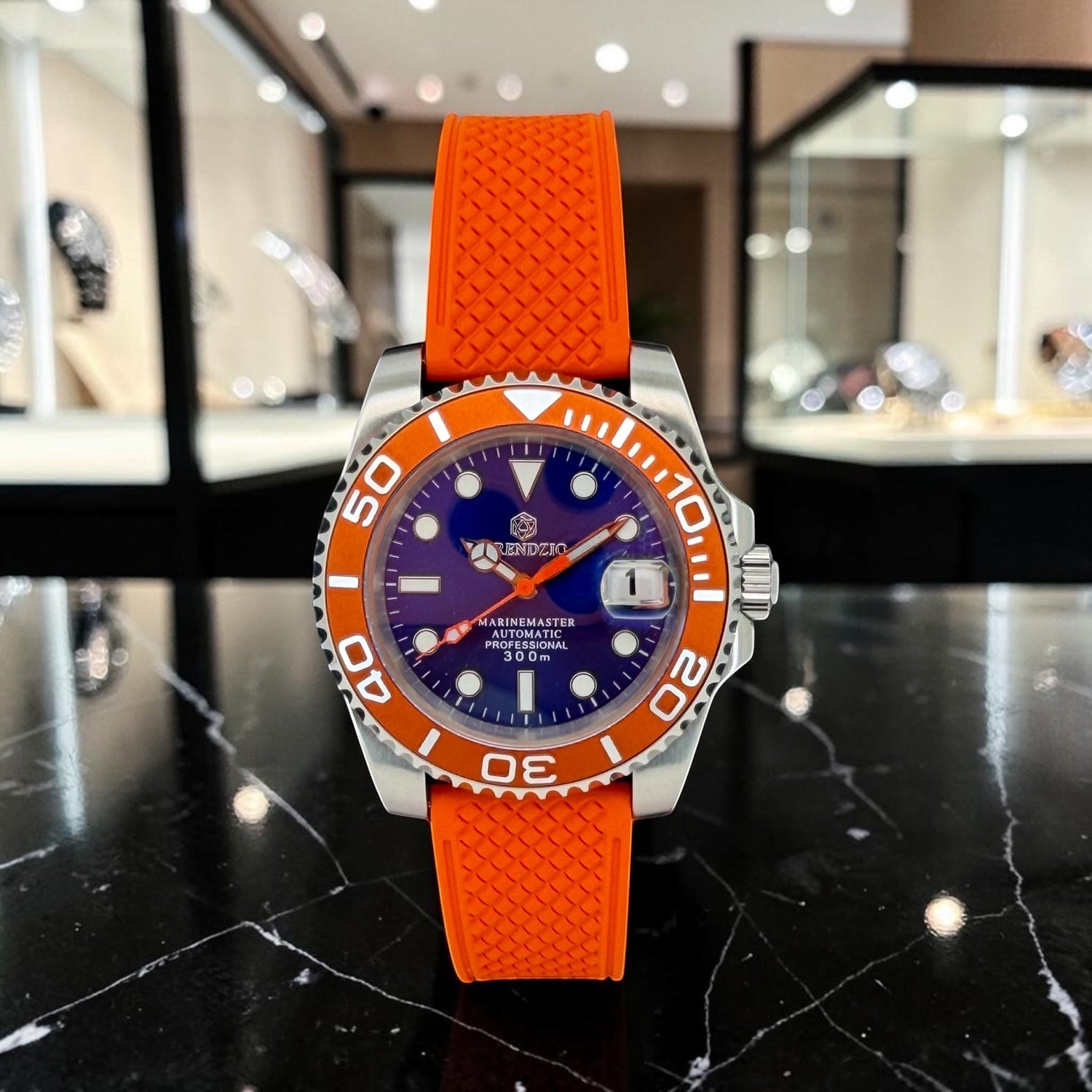 Trendzio Jewelry Blue Amber Mariner automatic watch with orange rubber strap, blue dial, and orange bezel. Features a date window.