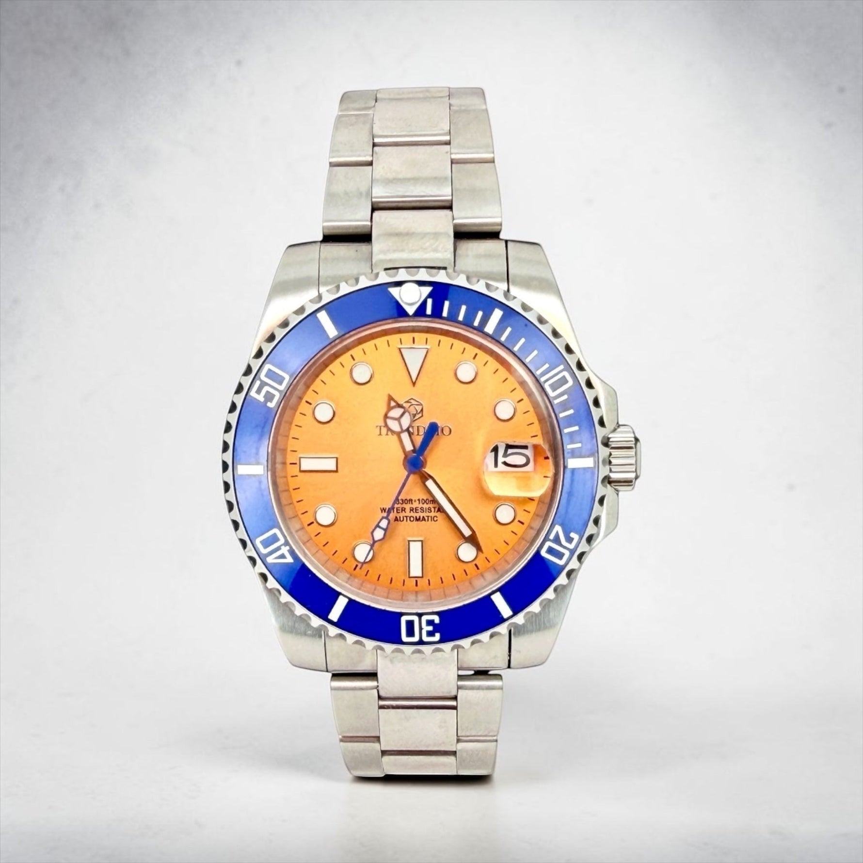Trendzio Jewelry Blue Amber Mariner watch with orange dial, blue bezel, stainless steel bracelet, and date window.