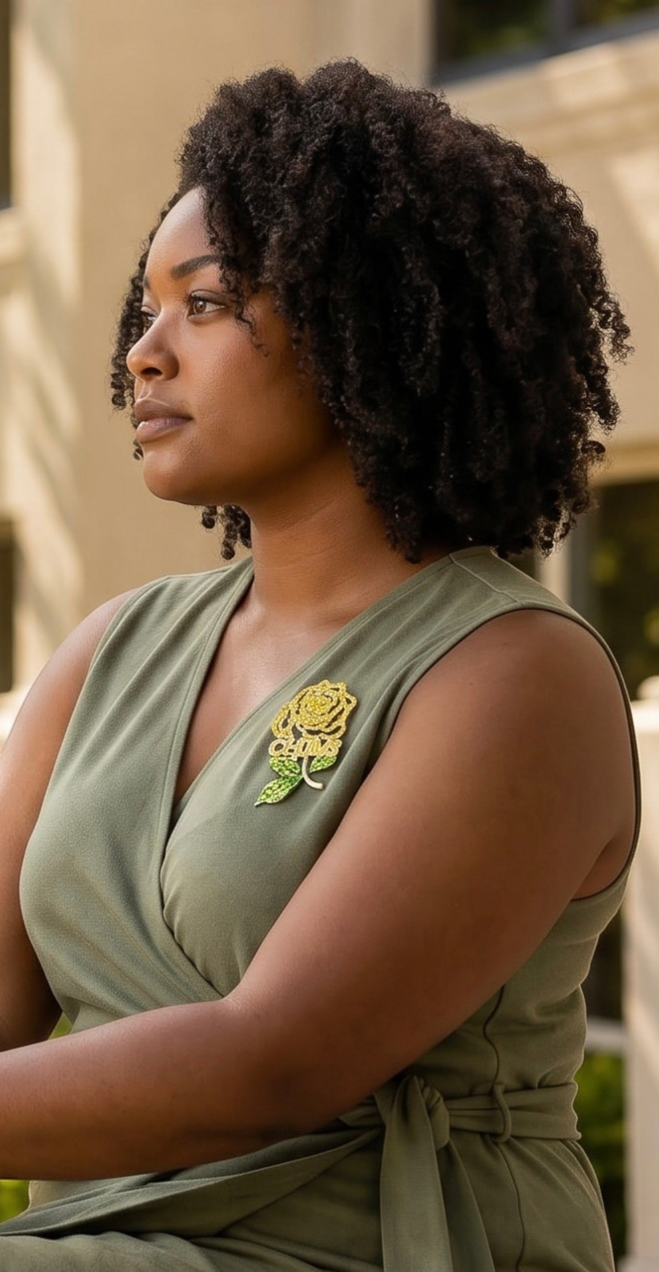 Model wearing a Trendzio Jewelry yellow and green crystal rose lapel pin with CHUMS lettering on a green dress.