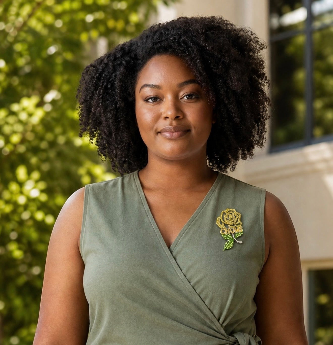 Trendzio Jewelry yellow and green crystal rose lapel pin worn by a woman in an olive green dress