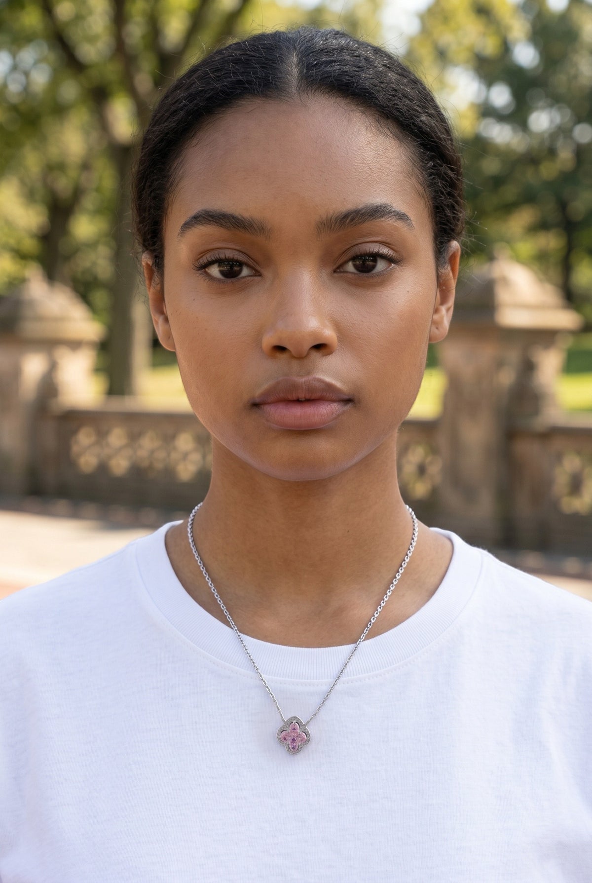 Trendzio Jewelry sterling silver clover necklace with pink CZ stones worn by a model in a park setting.