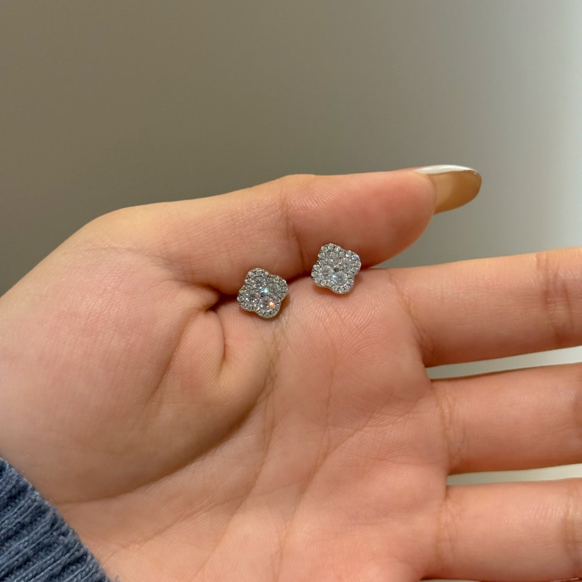 Trendzio Jewelry Ingrid clover moissanite flower stud earrings held in a hand, featuring sparkling 0.68ct stones.