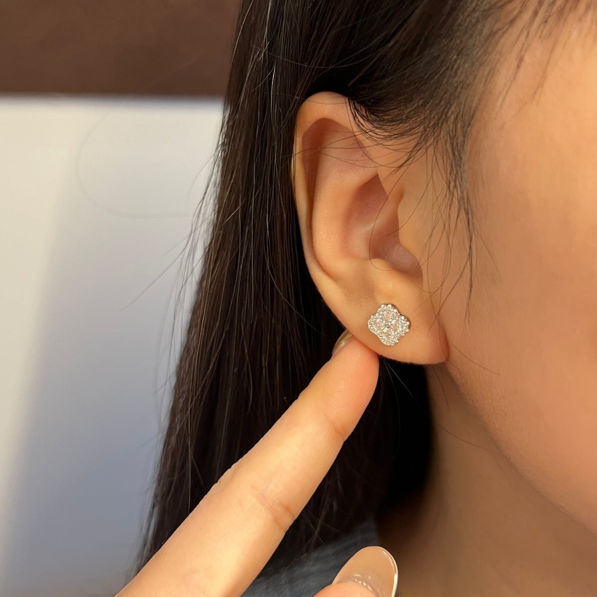 Trendzio Jewelry Ingrid clover moissanite flower stud earrings worn on a model's ear, featuring a 0.68 carat stone.