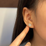 Trendzio Jewelry Ingrid clover moissanite flower stud earrings worn on a model's ear, featuring a 0.68 carat stone.