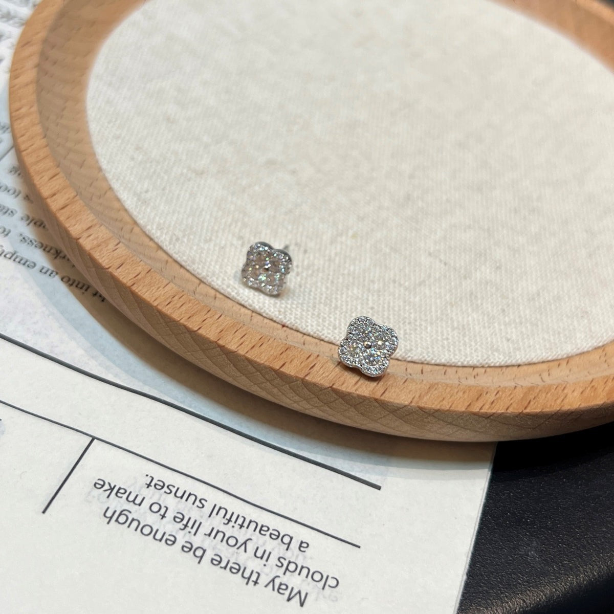 Trendzio Jewelry Ingrid Clover moissanite flower stud earrings with sparkling stones on a wooden display tray.