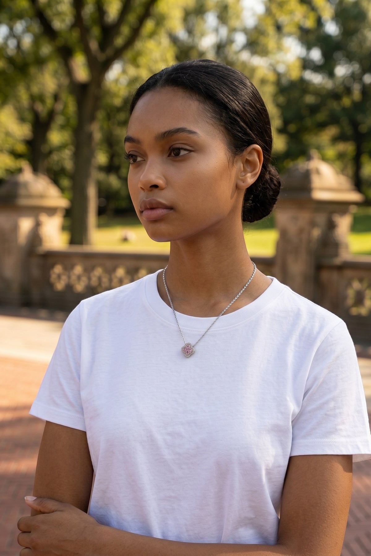 Model wearing a Trendzio Jewelry sterling silver Kaitlin clover necklace with pink and green CZ stones outdoors.