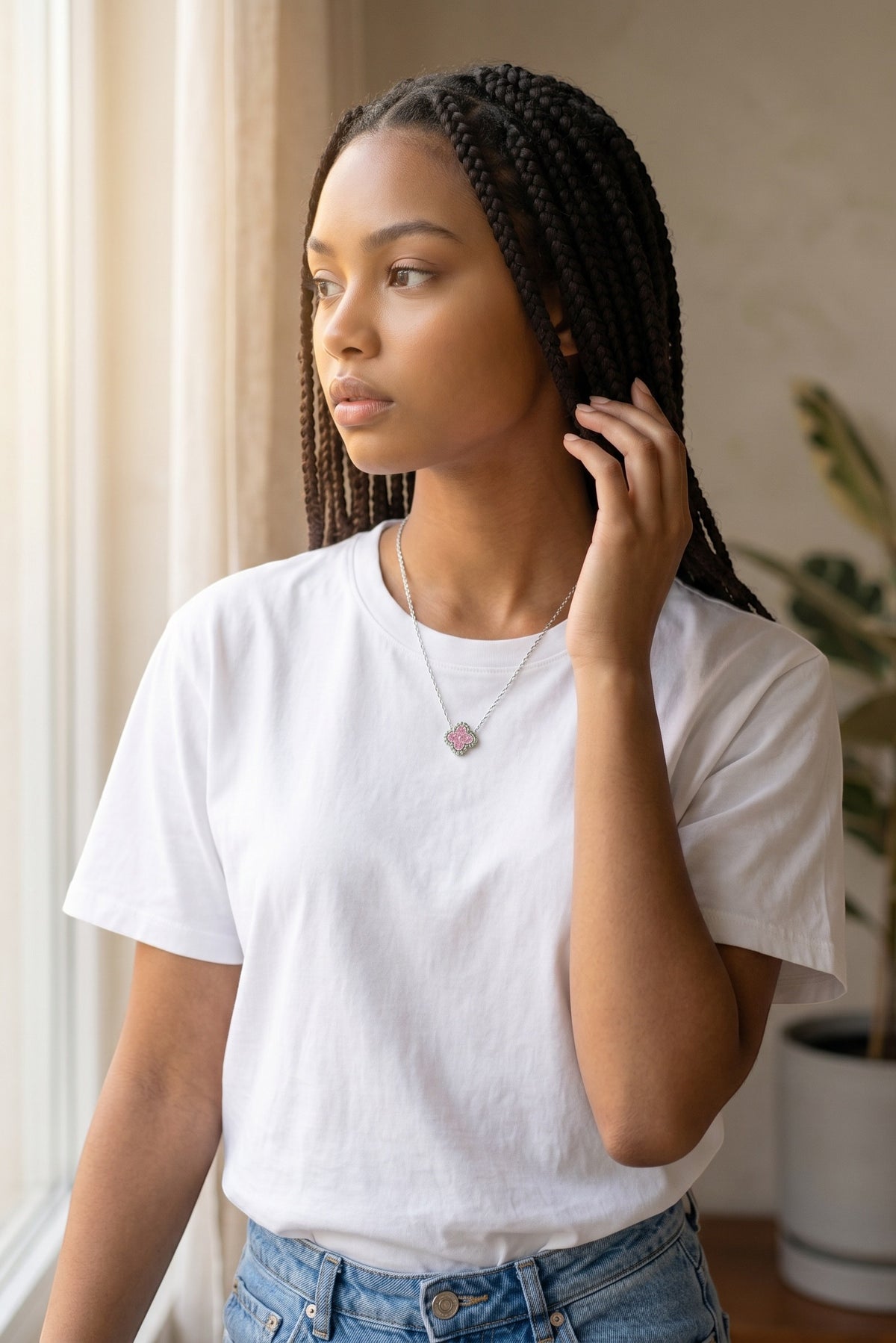 Trendzio Jewelry Kaitlin clover necklace in sterling silver with pink CZ stones worn by a woman in a white t-shirt.
