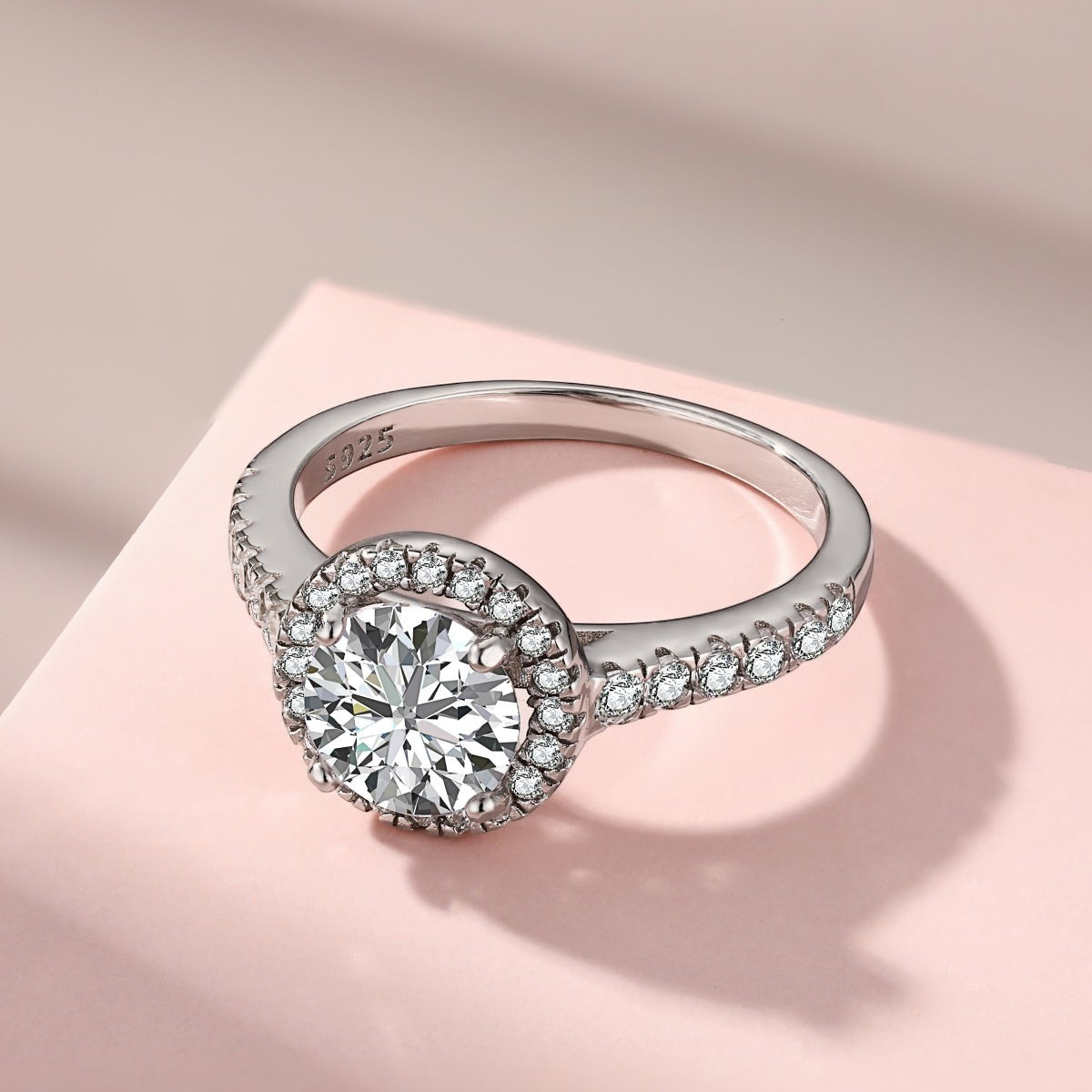 Trendzio Jewelry Lyra sterling silver ring featuring a round halo CZ diamond on a pavé band against a pink backdrop.