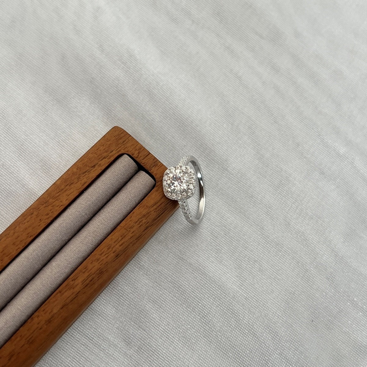 Trendzio Jewelry sterling silver Mira moissanite ring with a halo setting on a wooden display stand