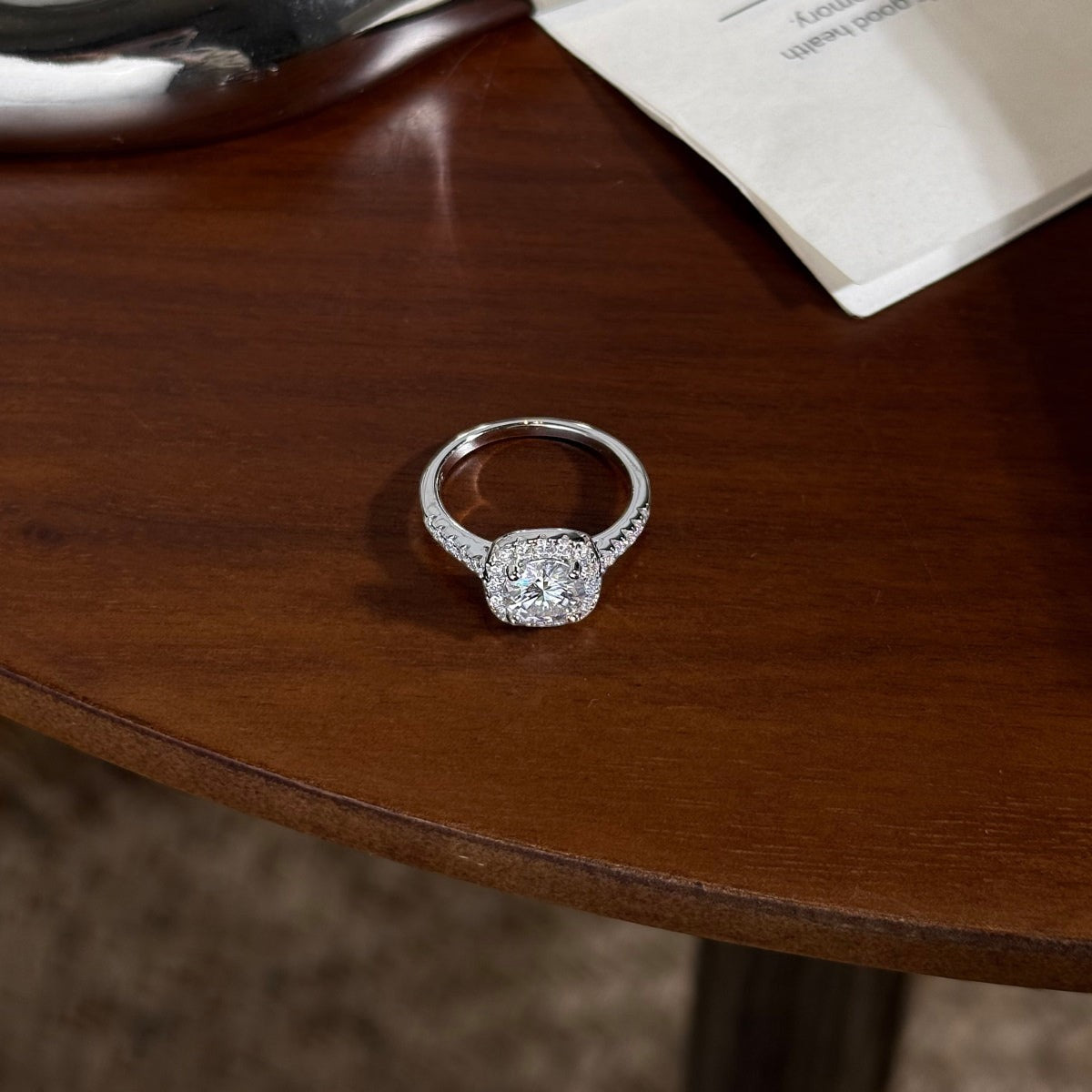 Trendzio Jewelry Mira moissanite ring in sterling silver with a sparkling halo setting on a wooden table
