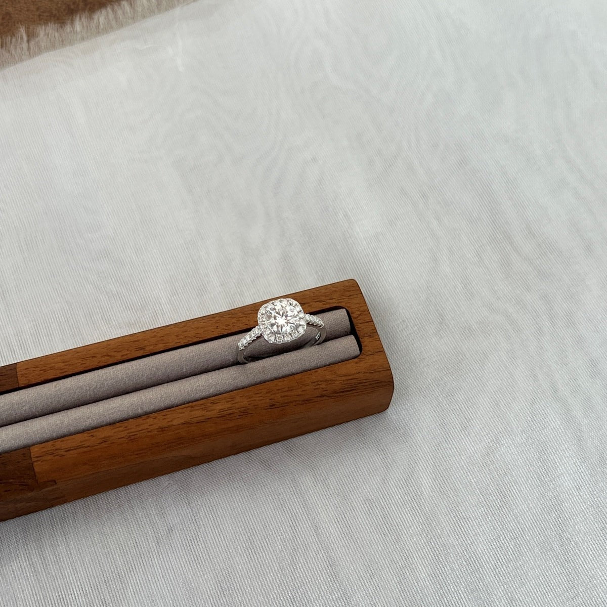 Trendzio Jewelry Mira moissanite ring in sterling silver with a cushion-cut halo setting on a wooden display stand.