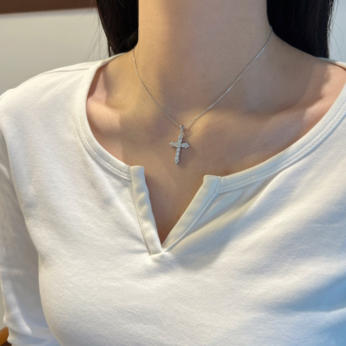 Trendzio Jewelry sterling silver moissanite cross necklace worn by a woman in a white top.