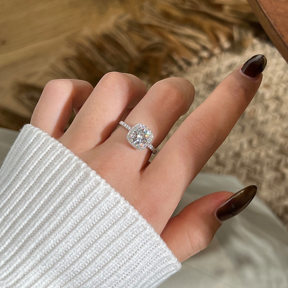 Trendzio Jewelry sterling silver cushion cut moissanite ring with halo setting on a hand wearing a white sweater