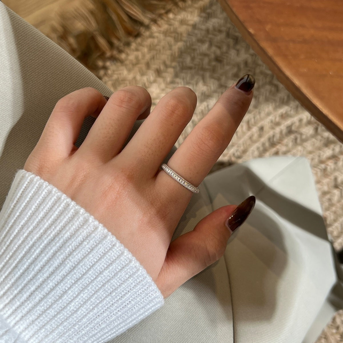 Trendzio Jewelry Nola sterling silver moissanite eternity band ring worn on a finger with a white sweater sleeve
