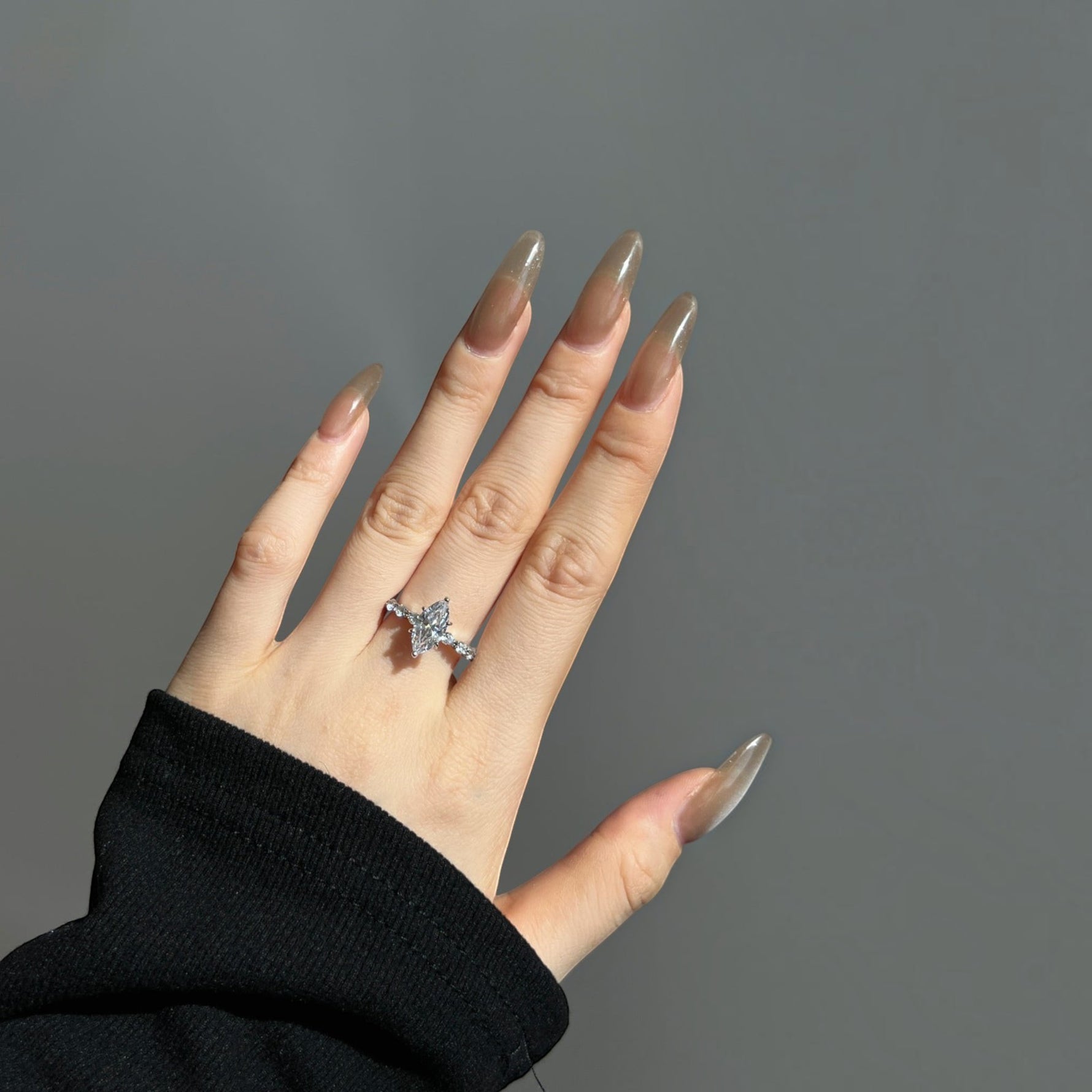 Trendzio Jewelry Uma CZ diamond ring in sterling silver with a marquise-cut stone on a hand with long manicured nails.