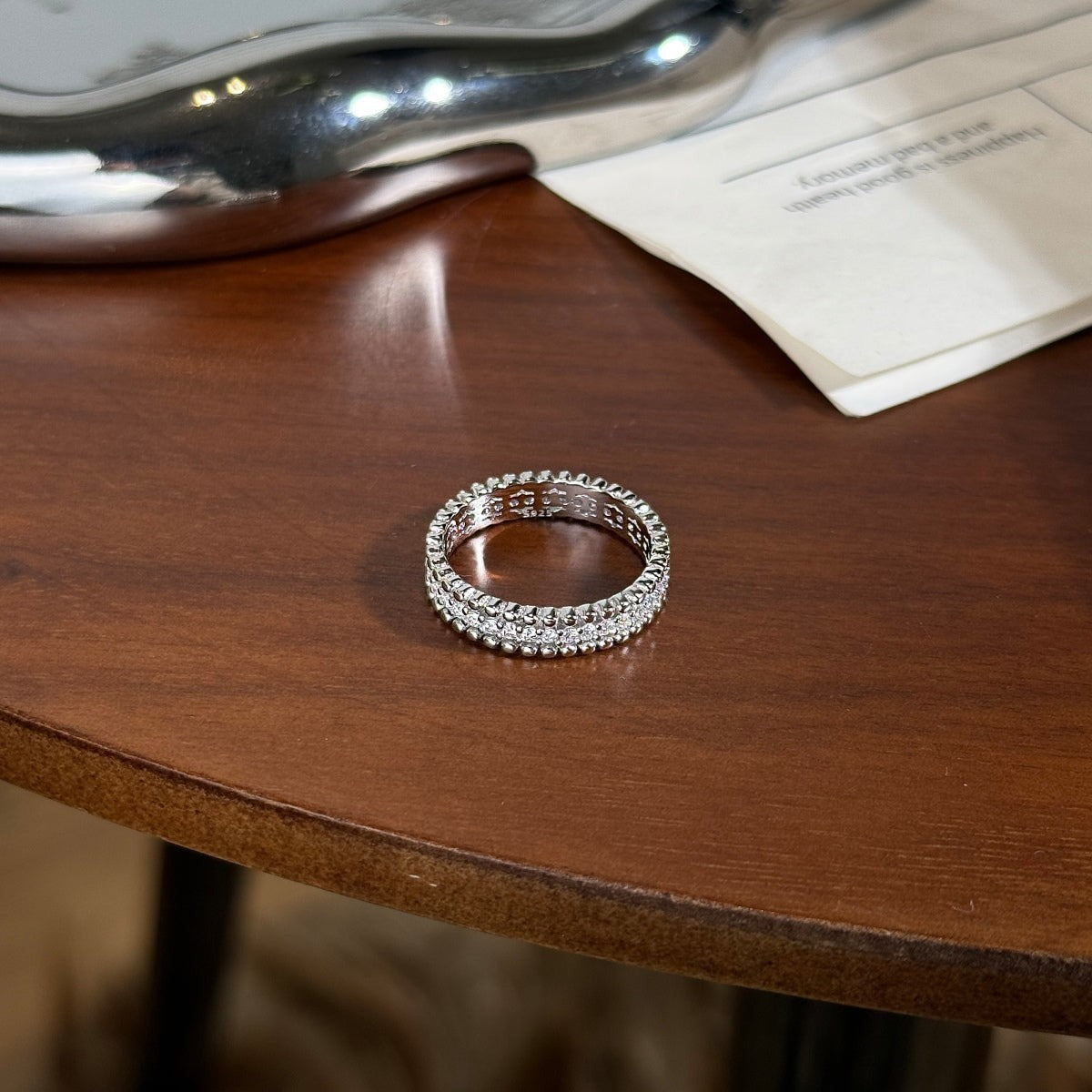 Trendzio Jewelry Zora moissanite diamond eternity ring in sterling silver resting on a wooden table.