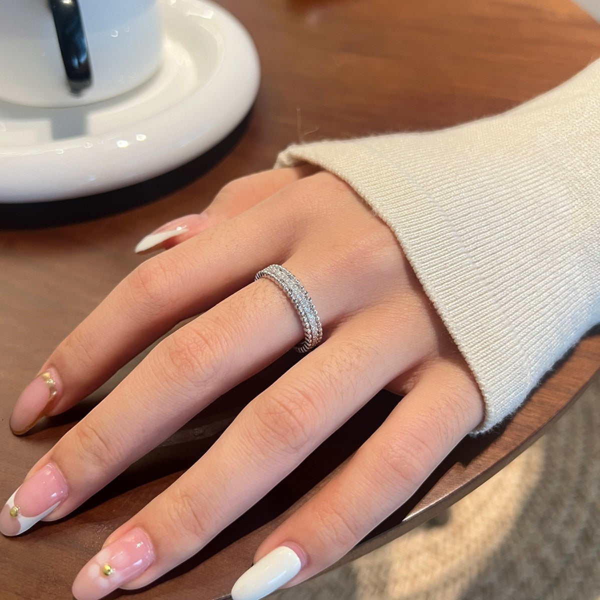 Trendzio Jewelry Zora moissanite diamond ring in sterling silver worn on a hand with a cream sweater sleeve.