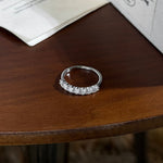 Trendzio Jewelry Zula sterling silver ring featuring a row of sparkling moissanite stones on a wooden table.