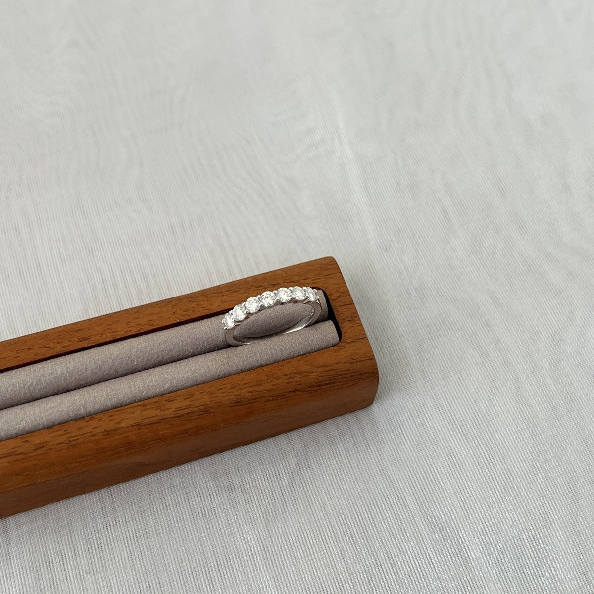 Trendzio Jewelry Zula sterling silver ring featuring a row of sparkling moissanite stones in a wooden display stand.