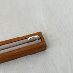 Trendzio Jewelry Zula sterling silver ring featuring a row of sparkling moissanite stones in a wooden display stand.