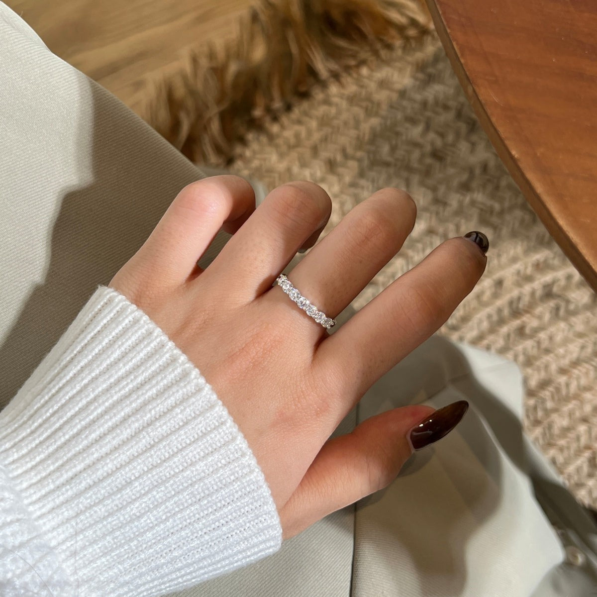 Trendzio Jewelry Zula moissanite eternity band in sterling silver worn on a finger with a white sweater sleeve.