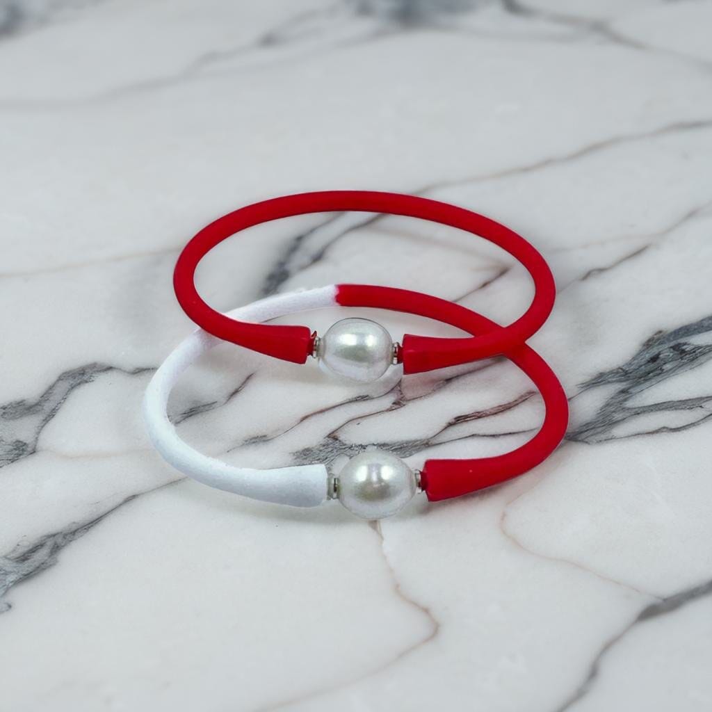 Elevate your style with these chic red and white bangle bracelets featuring elegant pearl accents, showcased on a luxurious marble background—timeless fashion meets modern elegance. 