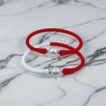 Elevate your style with these chic red and white bangle bracelets featuring elegant pearl accents, showcased on a luxurious marble background—timeless fashion meets modern elegance. 
