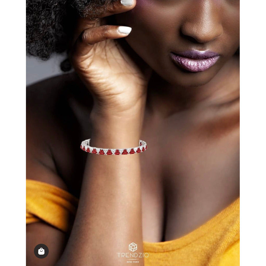 Close-up of a woman wearing the Red and White Trillion Bracelet, an elegant piece featuring alternating trillion-cut red ruby and cubic zirconia diamonds set in 925 sterling silver plated with rhodium. The bracelet stands out against her skin and complements her stylish look.